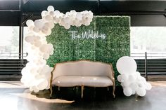 an arch made out of white balloons with the word teal wedding on it and two couches in front