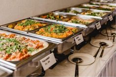 many trays of food are lined up on the buffet table