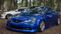 two blue cars parked in the woods next to each other