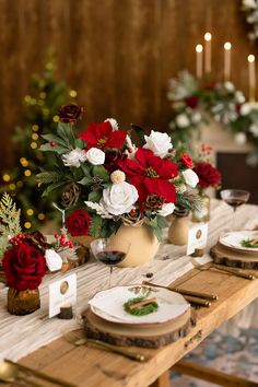 the table is set for christmas dinner with red and white flowers in vases on it