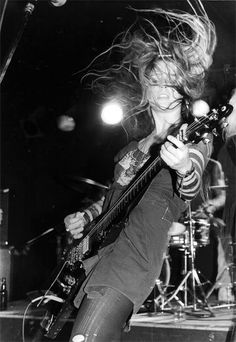 a man with long hair playing guitar on stage