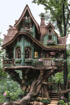 a tree house with lots of windows and flowers on the roof is surrounded by greenery