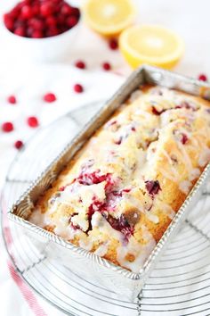 a loaf of lemon raspberry bread sitting on a wire rack next to some cranberries