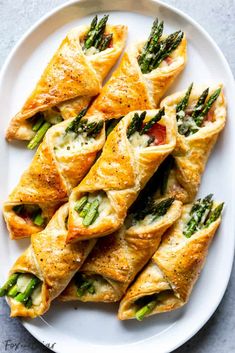 asparagus and prosciutto puff pastry rolls on a white platter