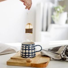 a person is sprinkling sugar into a cup on a cutting board with a spoon