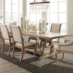 a dining room table with chairs and chandelier in front of large open windows