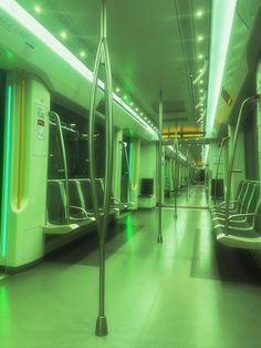 an empty subway car with green lights on the ceiling and metal railings in between