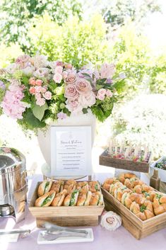 a table topped with trays of food next to a potted plant and flowers