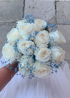 a bridal holding a bouquet of white roses and baby's breath blue accents