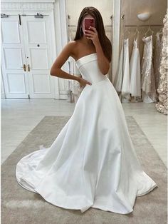 a woman taking a selfie while wearing a white wedding dress in front of a mirror