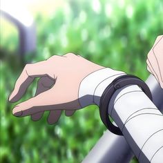 a person holding onto a metal rail with their hand on it's arm and green grass in the background