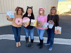 three girls in costumes holding up donuts and cupcakes