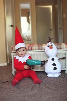 a young boy is playing with a blow dryer next to a snowman