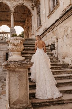 a woman in a wedding dress standing on some steps with her back to the camera