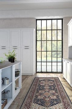 a kitchen with an orange flower rug on the floor and white cupboards behind it