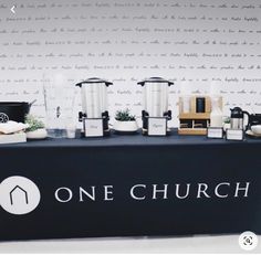 there is a one church sign on the table with coffee mugs and other items