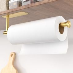 two rolls of toilet paper are hanging on the wall next to a wooden cutting board