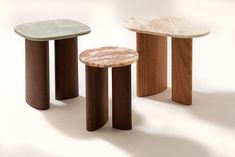 three tables with marble tops on each side and wood bases in different colors, sizes and shapes