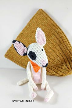 a crocheted rat sitting on top of a table next to a folded napkin