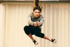 a woman is jumping in the air on a trampoline with her legs spread out