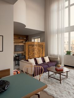 a living room filled with furniture next to a large window covered in white drapes