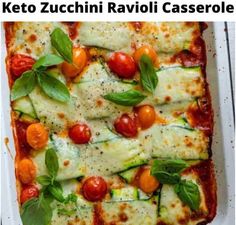 a casserole dish with zucchini, tomatoes and basil leaves on top