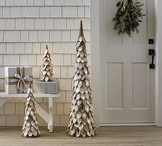 three small christmas trees sitting in front of a house