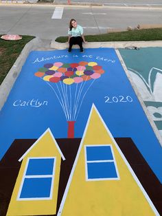 a woman sitting on top of a blue and yellow painted area next to a street