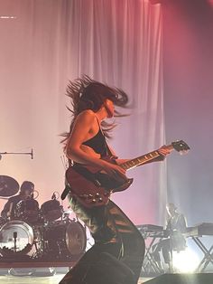 a woman with long hair playing guitar on stage