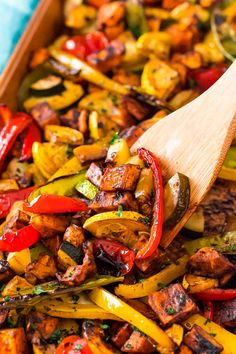 a wooden spatula scooping food out of a casserole dish with vegetables