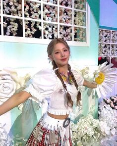 a woman in a white top and skirt standing next to flowers