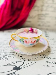 a teacup with pink flowers is sitting on a saucer