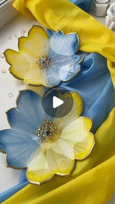 two blue and yellow flowers sitting on top of a white table next to each other