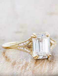 an emerald - cut diamond ring sits on top of a piece of furnishing