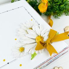 a white box with yellow ribbon and flowers on it next to other items that include nuts