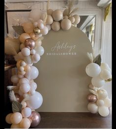 balloons are arranged in the shape of an arch with leaves and flowers on it, along with other decorations