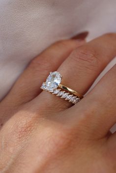 a woman's hand with a gold ring and diamond band on her left hand