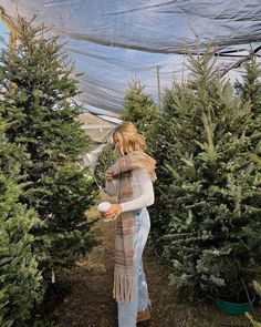 a woman is picking out christmas trees at the tree farm