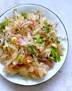 a white plate topped with salad on top of a table