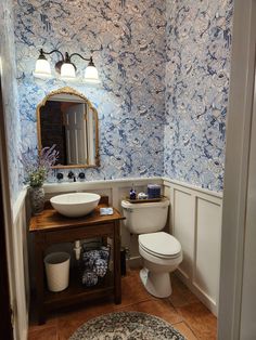 a white toilet sitting next to a sink in a bathroom under a vanity with a mirror above it