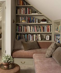 a living room filled with lots of books on top of a book shelf next to a couch