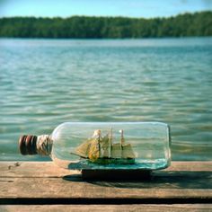 a ship in a bottle sitting on top of a wooden dock