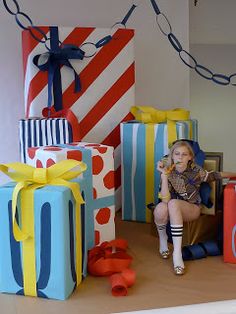 a woman sitting on a chair in front of many wrapped presents with ribbons and bows