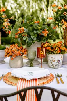 the table is set with orange flowers and place settings