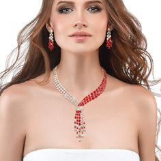 This exquisite set, draped in radiant yellow gold, exudes a timeless charm, while the sparkling Diamondeau®, flawless simulated diamond, adds a touch of sophistication and glamour. At the heart of this ensemble is a necklace that elegantly flows around the neck, reminiscent of a graceful tie, yet imbued with a sense of femininity and grace. The red and white gems create a mesmerizing contrast that captivates the eye and commands attention. Completing the set are the matching earrings. Each earri Elegant Crystal Backdrop Necklace As Gift, Elegant Crystal Backdrop Necklace For Gift, Elegant Diamond Backdrop Necklace For Parties, Exquisite Crystal Jewelry Sets For Parties, Dazzling Bridal Necklace For Celebration, Celebration Cubic Zirconia Jewelry Sets, Sparkling Stones Jewelry Sets For Celebration, Fine White Jewelry With Rhinestones, Fine Jewelry White Rhinestone Jewelry