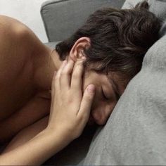 a man laying in bed with his hand on his face as if he were asleep