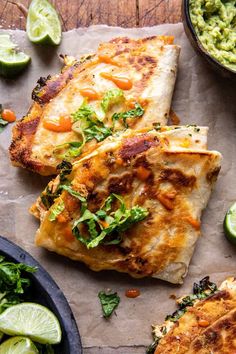 two quesadillas on parchment paper next to bowls of guacamole