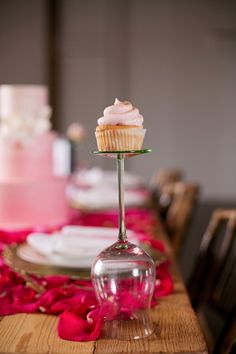 a cupcake sitting on top of a table next to a wine glass and plate