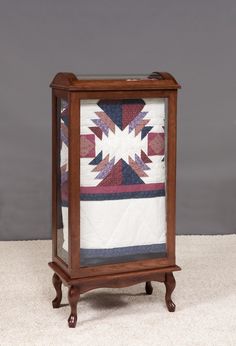 a small wooden cabinet with a quilt on it's front and bottom panel, in the shape of a star