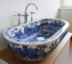 a blue and white bowl sink sitting on top of a wooden counter next to a window